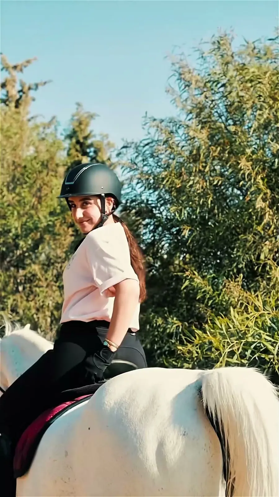 مشهد من فيديو محتوى لبراند فروسية يُظهر متدرّبة مع حصان في الإسطبل والميدان