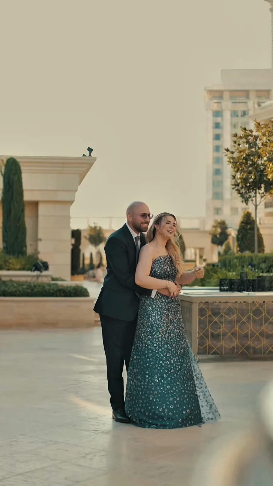 مشهد من فيلم لثنائي بلباس سهرة يسيران عند الغروب أمام واجهة فندق